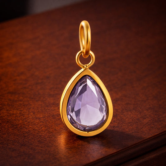 Gold pendant with a purple teardrop-shaped gemstone on a wooden surface
