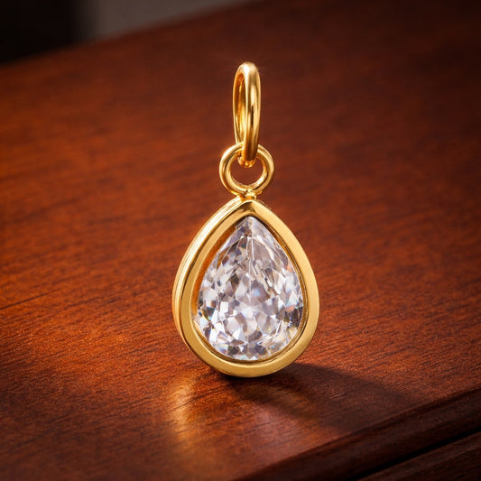 Gold pendant with a clear gemstone on a wooden surface
