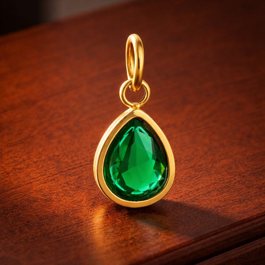 Gold pendant with a green gemstone on a wooden surface