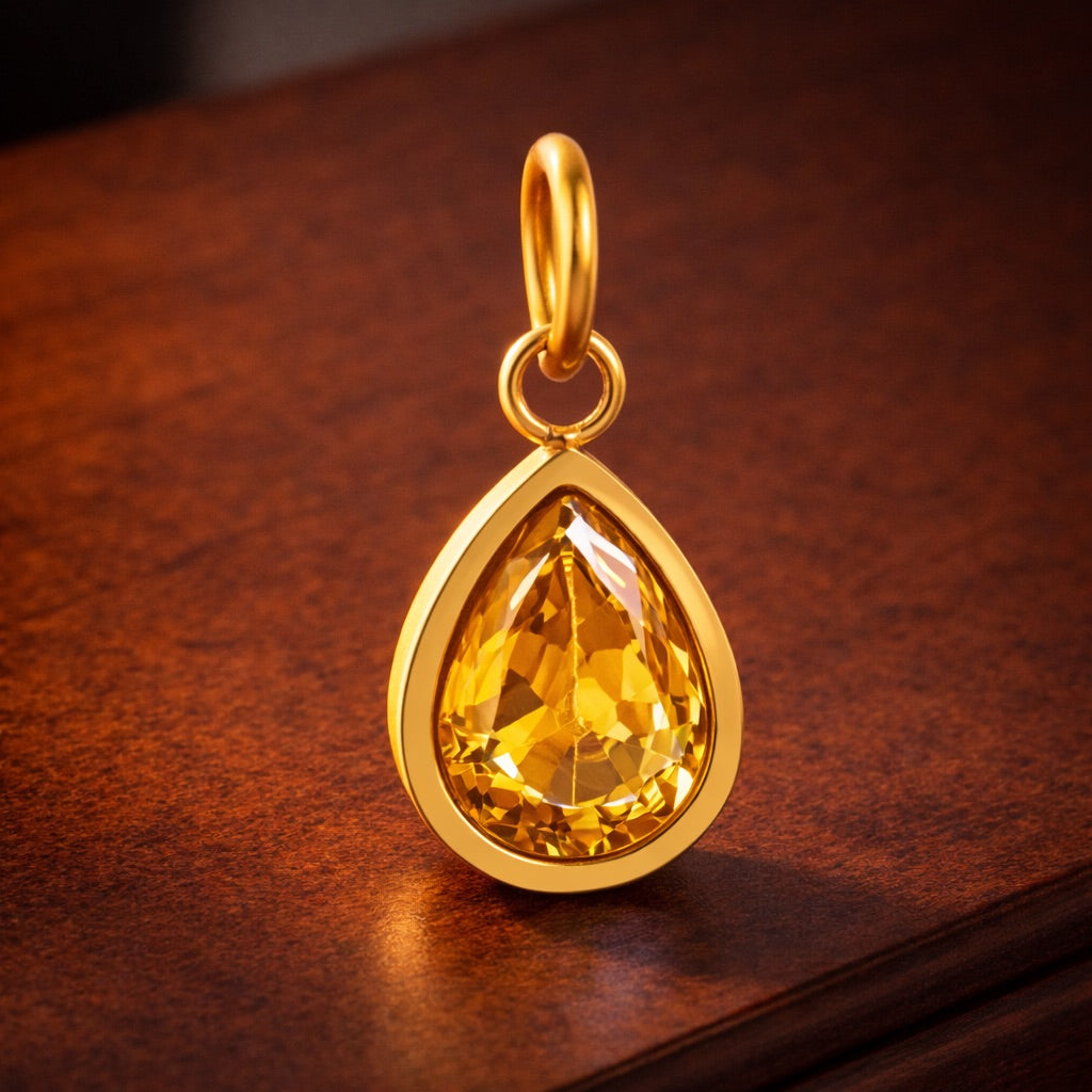 Gold pendant with a yellow gemstone on a wooden surface