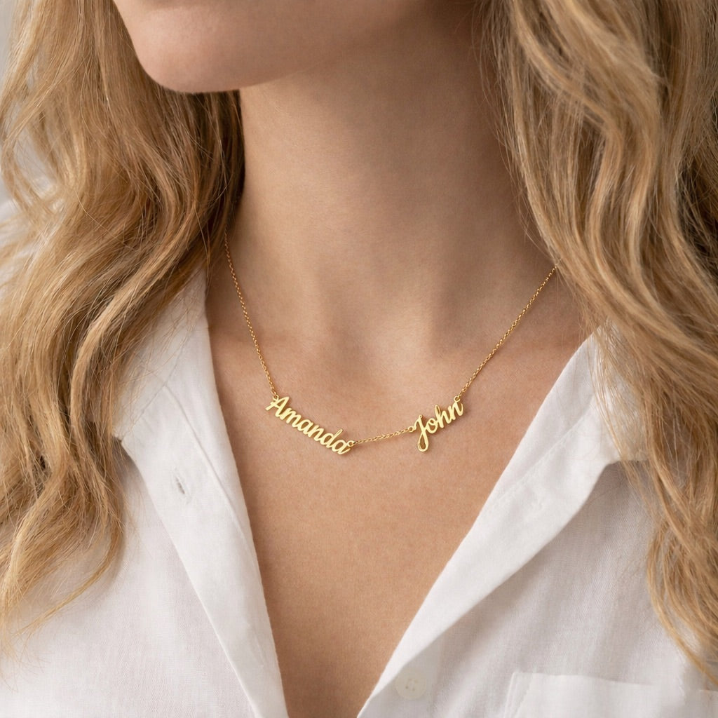 Gold name necklace with 'Amanda' and 'John' on a person wearing a white shirt.