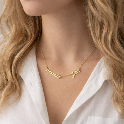 Gold name necklace with 'Amanda' and 'John' on a person wearing a white shirt.
