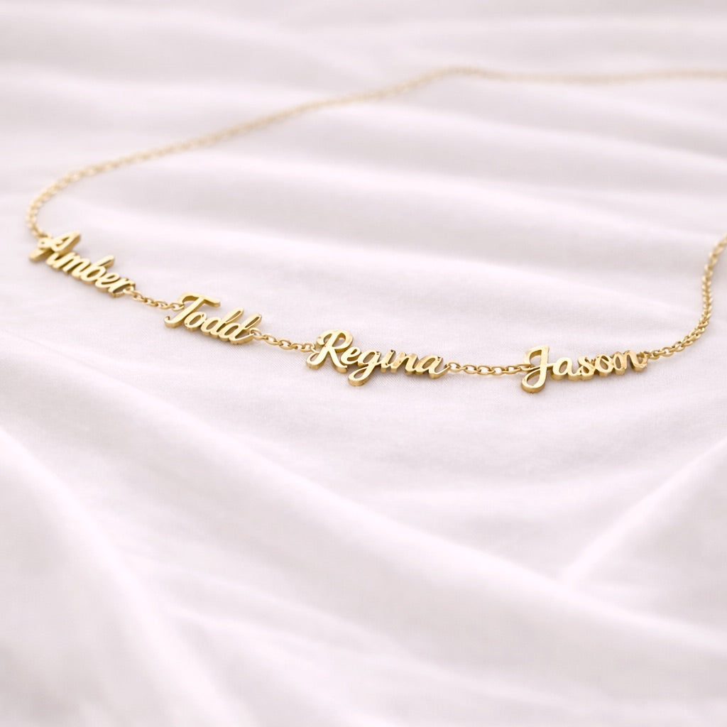 Gold name necklace on a white satin background