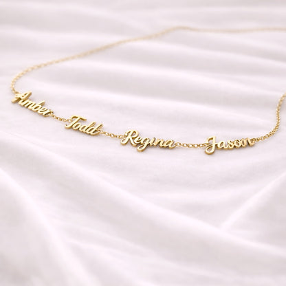 Gold name necklace on a white satin background