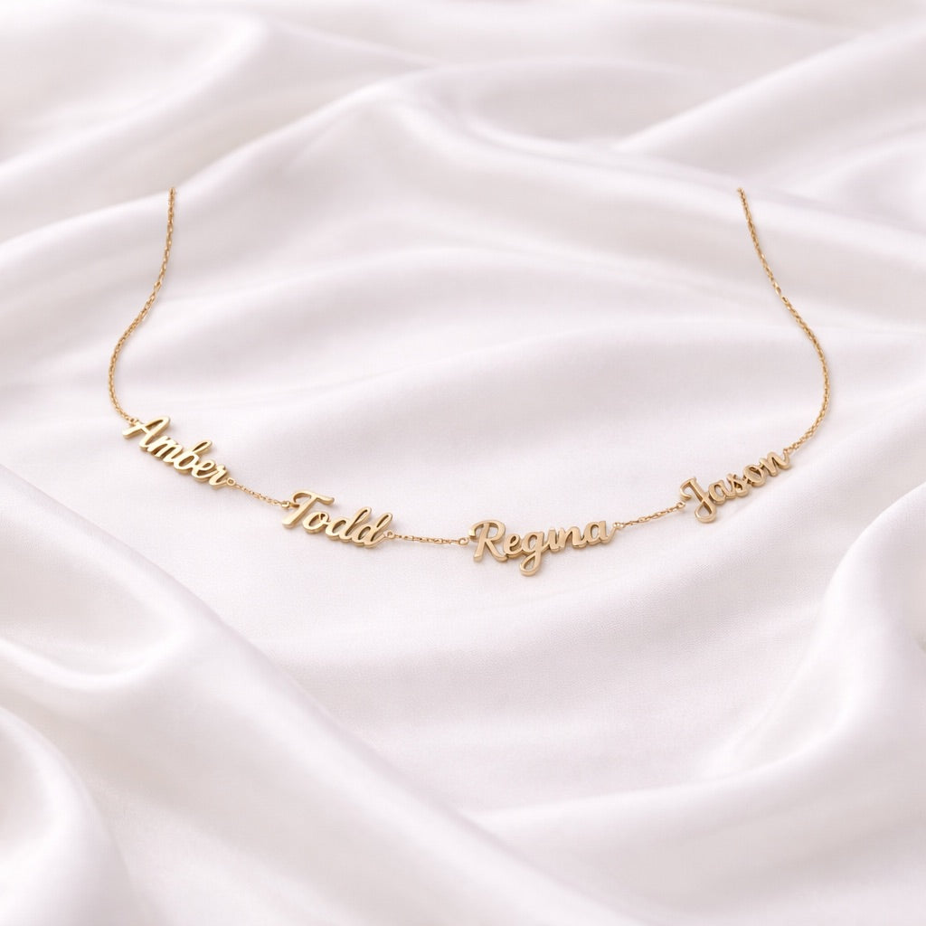 Customized gold name necklace on a white satin backdrop