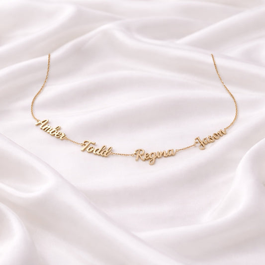 Customized gold name necklace on a white satin backdrop