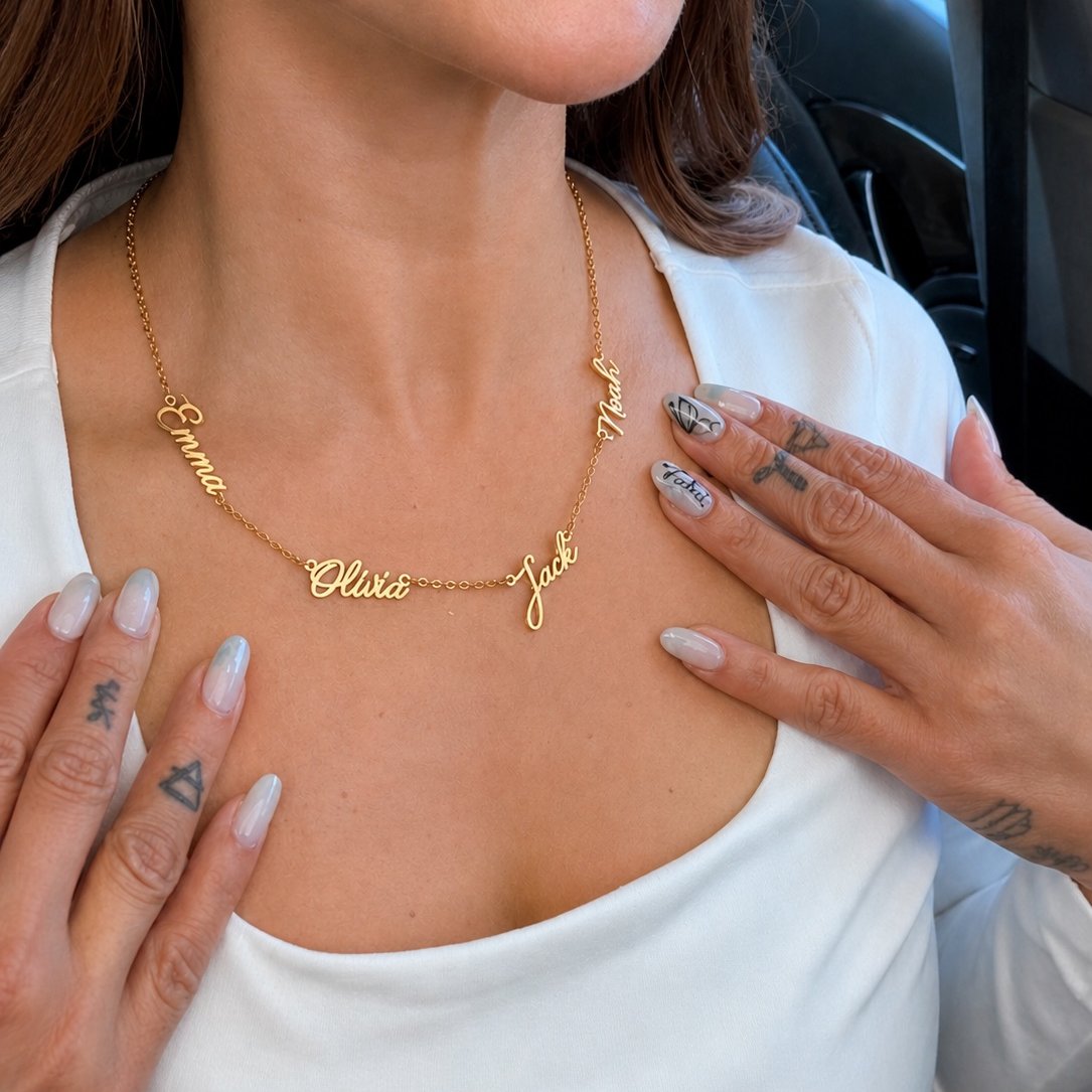 Gold personalized name necklace on a woman wearing a white top