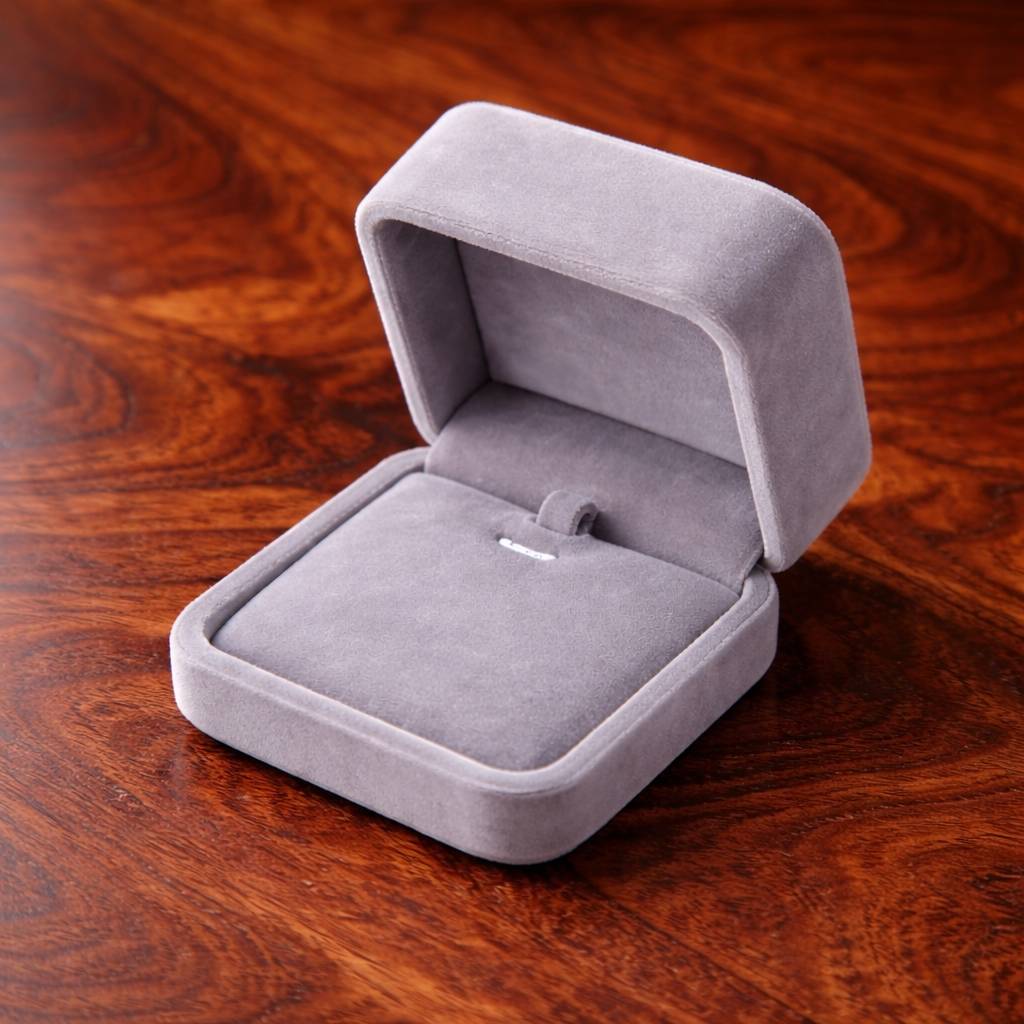 Gray velvet jewelry box with a ring on a wooden surface